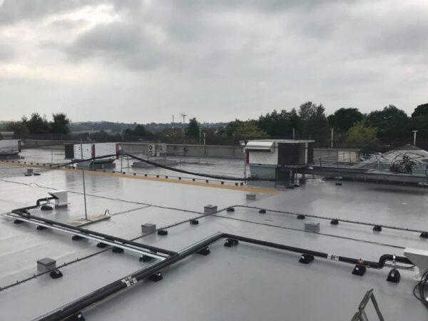 Liquid-applied flat roof with pipe supports and rooftop units
