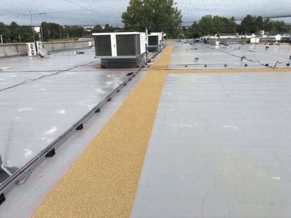 Flat roof with a liquid-applied membrane and a textured walkway to rooftop equipment