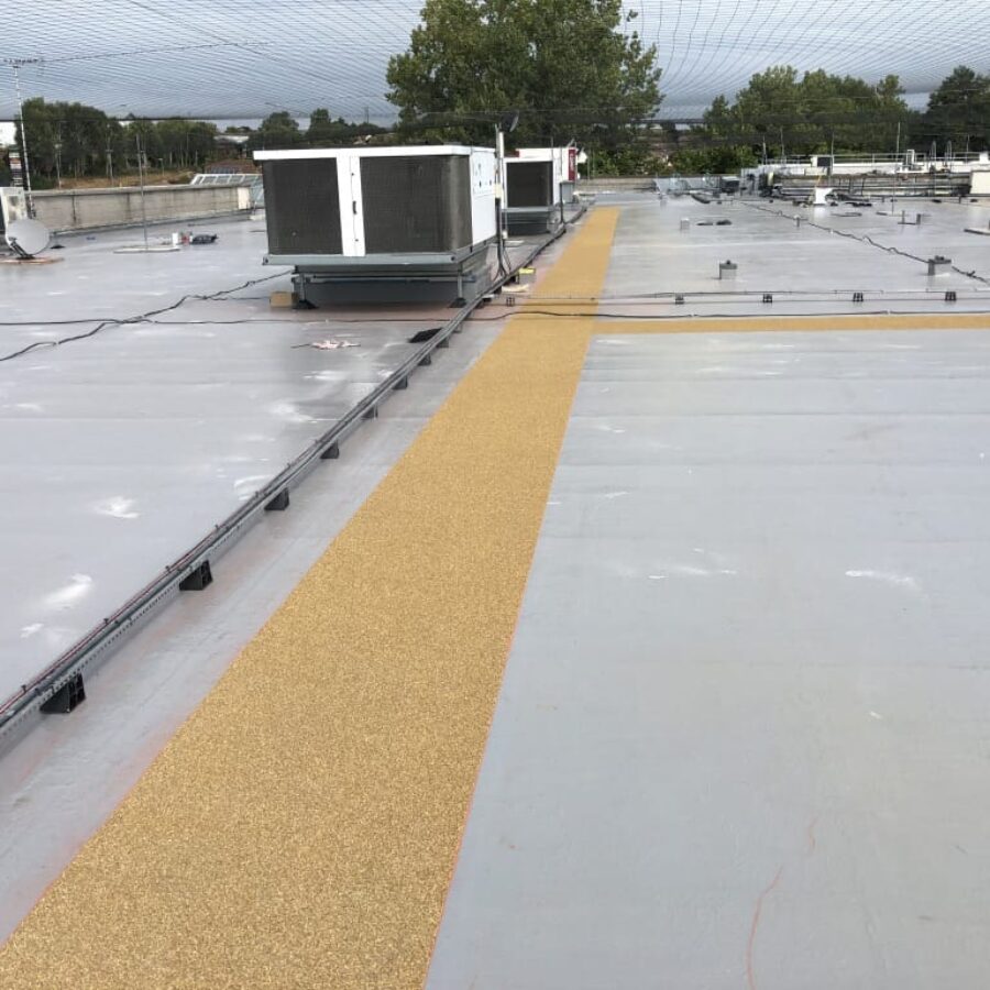 Flat roof with a liquid-applied membrane and a textured walkway to rooftop equipment