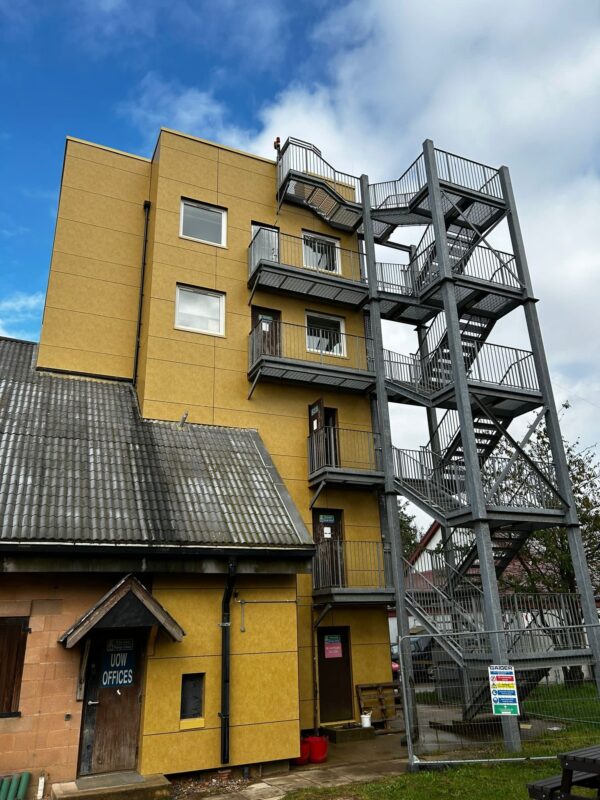 Reclad tower beside an older pitched-roof building