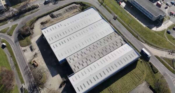 Aerial view of a large industrial roof part-way through replacement, with new metal roof bays and skylights