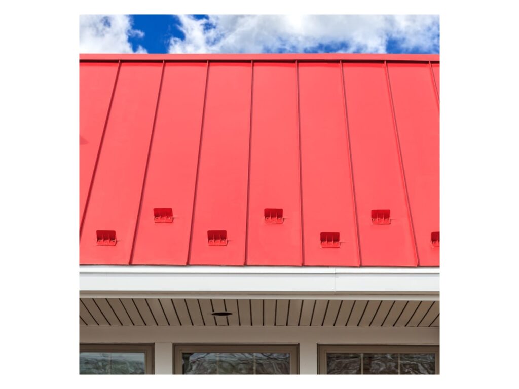 Red metal panel roof installed on a building with visible fastening strips