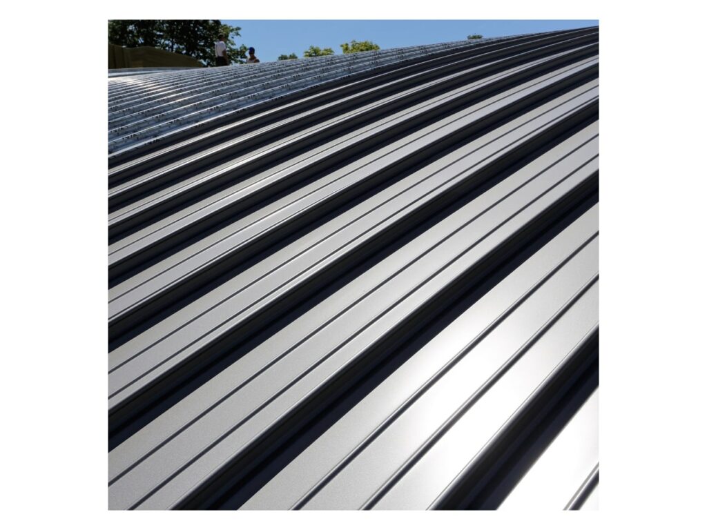 Standing seam metal roof panels installed on a curved building roof with ribs running up the slope