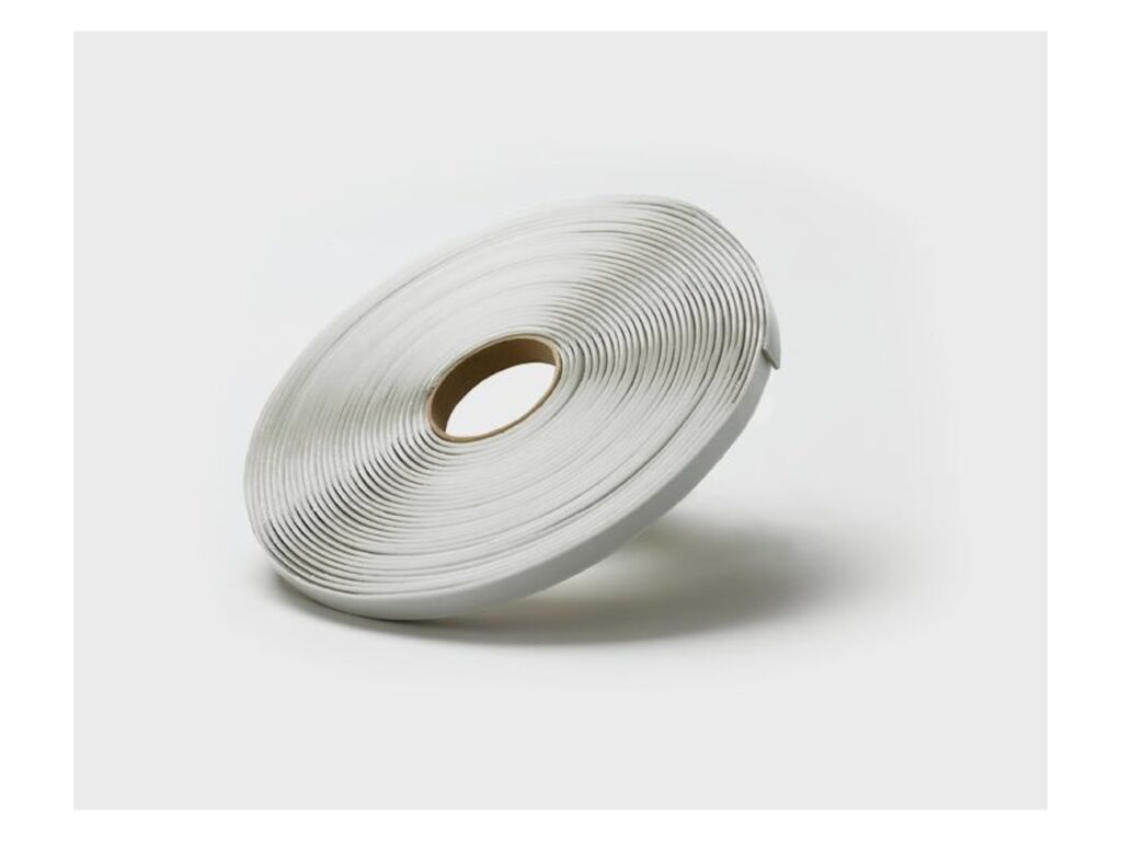 Roll of off-white butyl sealant tape standing on its edge against a plain light background
