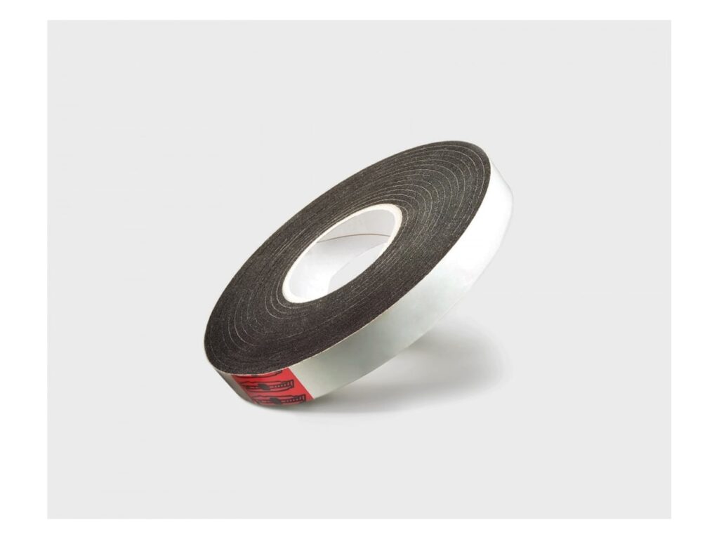 Roll of black X-Seal foam tape with white release paper on its side